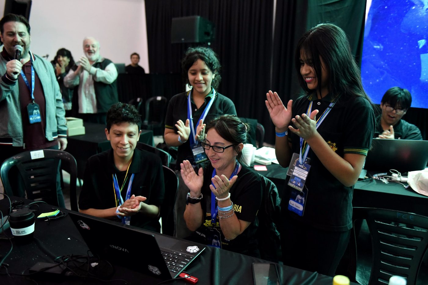 Un equipo festejando alrededor de sus computadoras