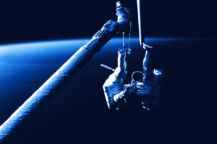 Dos astronautas trabajando fuera de la nave, sobre el limbo de la Tierra