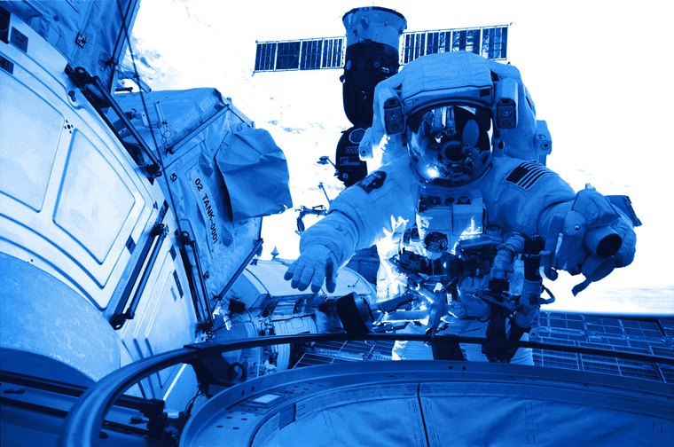 Astronauta durante una actividad extravehicular, con la estación reflejada en el visor